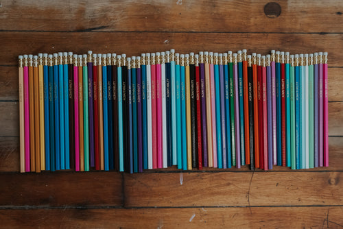 Colorful pencils arranged in a line on a wooden surface